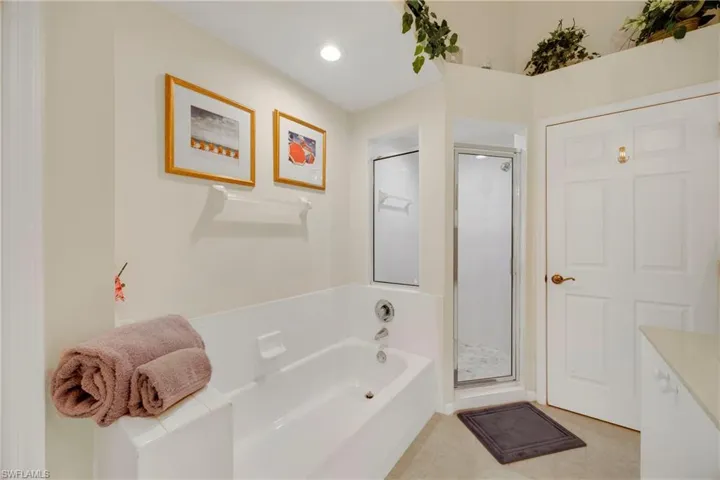 Bathroom featuring tile patterned floors, a stall shower, a bath, vanity, and recessed lighting