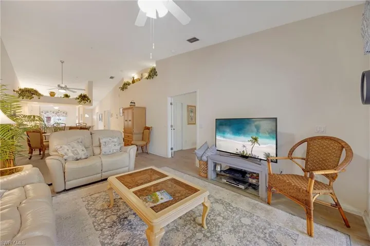 Living area with high vaulted ceiling, baseboards, a ceiling fan, and visible vents