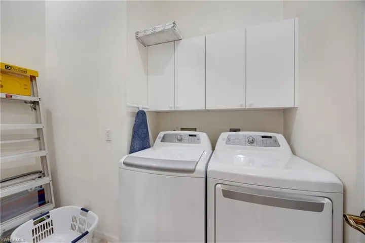Clothes washing area featuring cabinet space and washer and clothes dryer