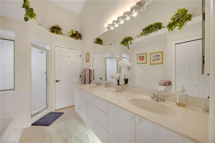 Bathroom with double vanity, a shower stall, tile patterned floors, and a sink