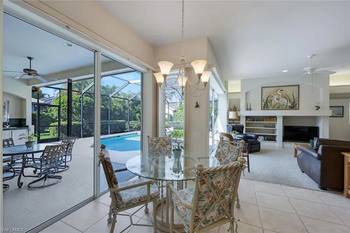 Tiled dining area with ceiling fan with notable chandelier and a fireplace