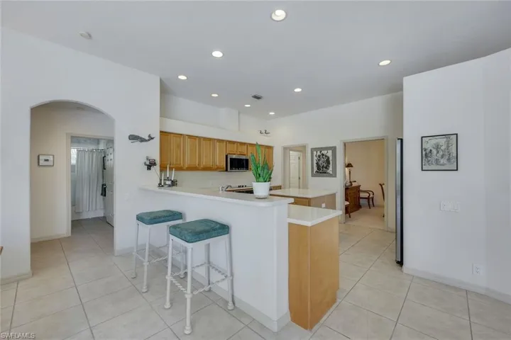 Kitchen featuring a kitchen breakfast bar, light tile patterned flooring, kitchen peninsula, and backsplash