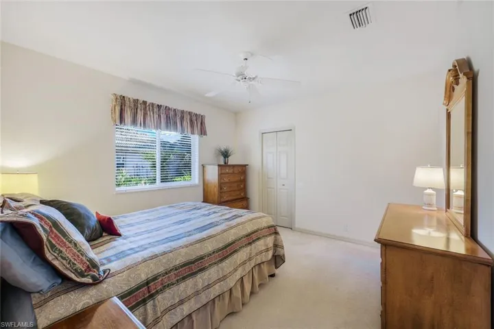 Bedroom with ceiling fan, light colored carpet, and a closet
