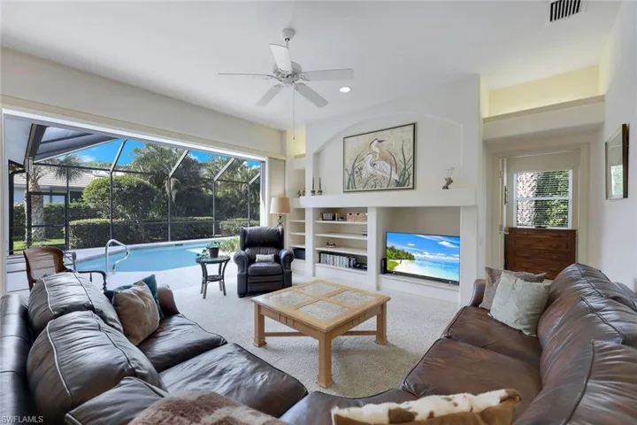 Living room with built in shelves, carpet floors, and ceiling fan