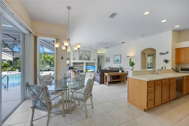 Dining area featuring sink, light tile patterned floors, and ceiling fan with notable chandelier