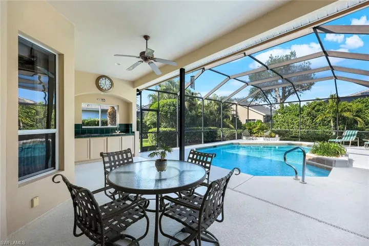 View of swimming pool featuring a lanai, exterior bar, ceiling fan, exterior kitchen, and a patio area