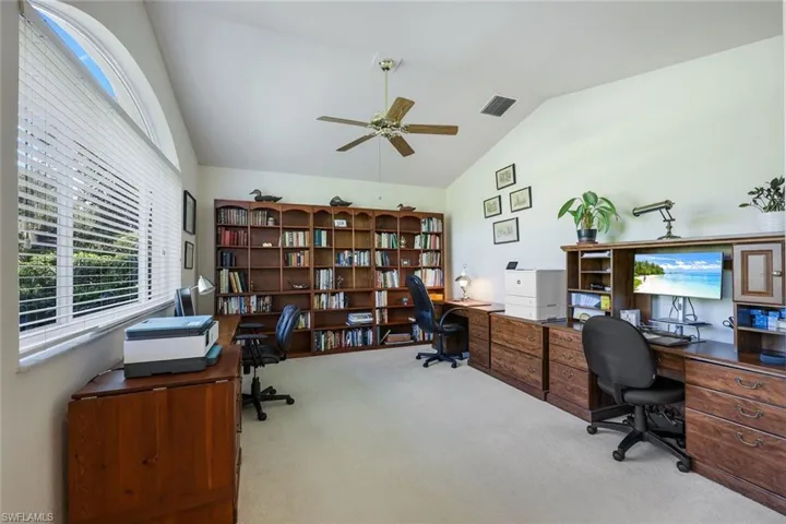 Home office featuring light carpet, ceiling fan, and lofted ceiling