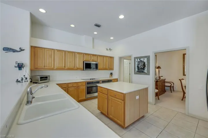 Kitchen with light tile patterned floors, a center island, stainless steel appliances, and sink