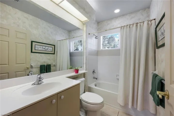 Full bathroom with toilet, vanity, shower / tub combo with curtain, and tile patterned flooring