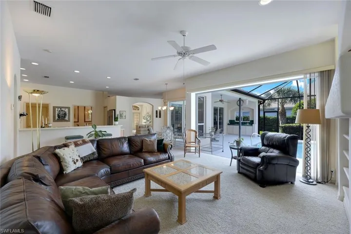 Carpeted living room featuring ceiling fan with notable chandelier