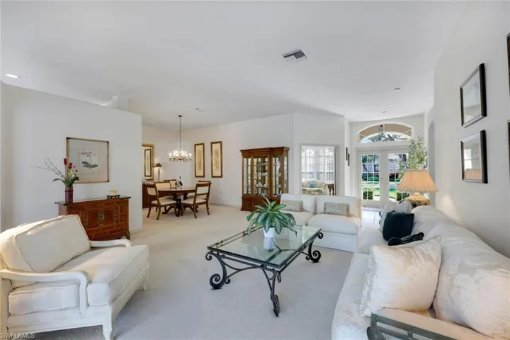 Living room featuring a notable chandelier, light carpet, and french doors