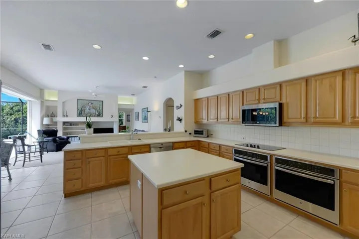 Kitchen with kitchen peninsula, tasteful backsplash, stainless steel appliances, a center island, and light tile patterned flooring