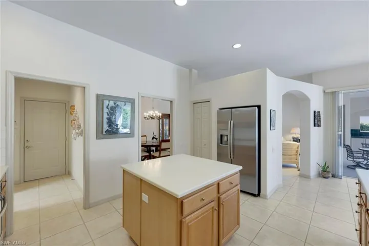 Kitchen with stainless steel fridge, light tile patterned floors, a kitchen island, and a notable chandelier