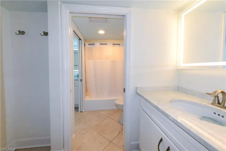 Bathroom with vanity, toilet, tile patterned floors, shower / bath combo with shower curtain, and recessed lighting