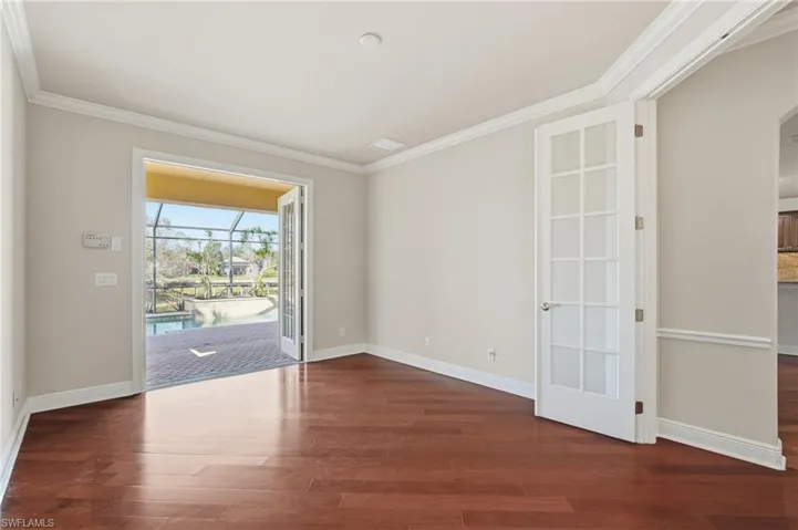 Den with crown molding, and wood finished floors leads to pool area