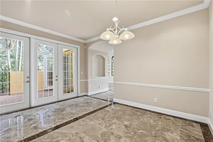 Dining area with a chandelier, ornamental molding, arched walkways, french doors leading to side patio, and inlaid floor details