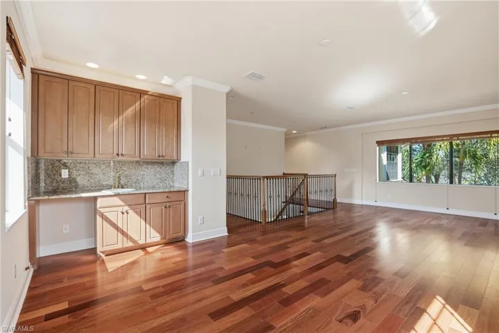 Loft area with open floor plan, backsplash, light wood-style floors, wood finish cabinets, and ornamental molding