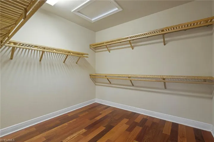 Primary walk in closet with attic access and wood-type flooring