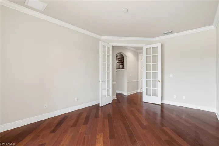 Den with French doors, wood-style floors, and crown molding