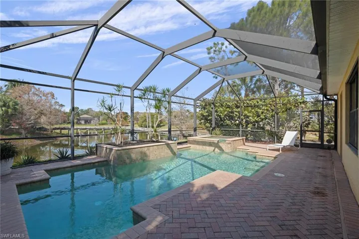 Combined pool / hot tub featuring a sunroom, a patio area, glass enclosure, and a water view