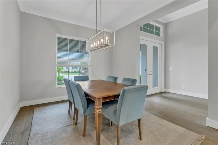 Dining area featuring a custom chandelier, french doors, crown molding, and light hardwood floors