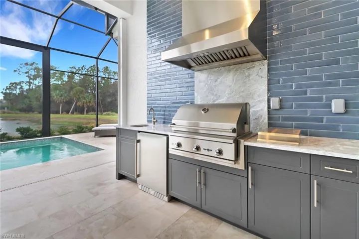 View of patio featuring custom grill, tiled backsplash, wine cooler and wet sink.