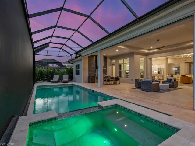Pool at dusk featuring an in ground hot tub, a patio area, an outdoor living space, a lanai, and ceiling fan.