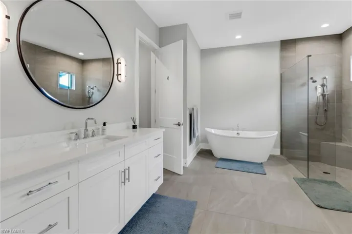 Primary bathroom with glass walk in shower, separate tub bath and vanity.