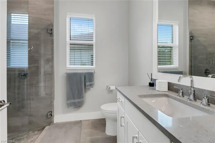 Guest bathroom with a walk in shower including a glass shower, white cabinets and custom vanity.