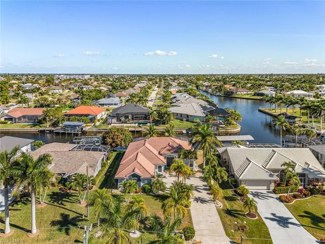 Aerial view showcasing the property's location along a canal, surrounded by mature palm trees and residential properties
