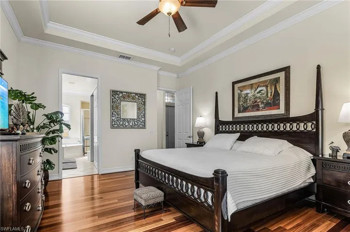 This room features gleaming hardwood floors and a tray ceiling with a ceiling fan