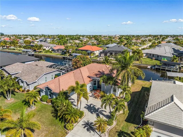 The property features a well-maintained lawn with tropical landscaping and a paved driveway