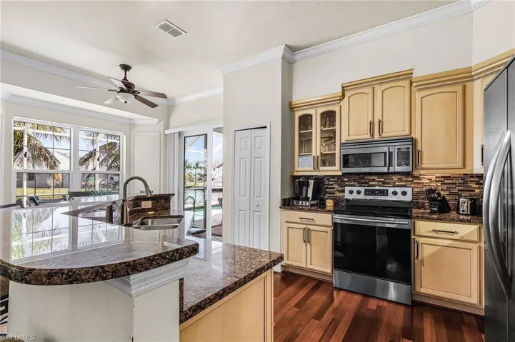 The kitchen features a large island with a stone countertop, a ceiling fan, and hardwood floors