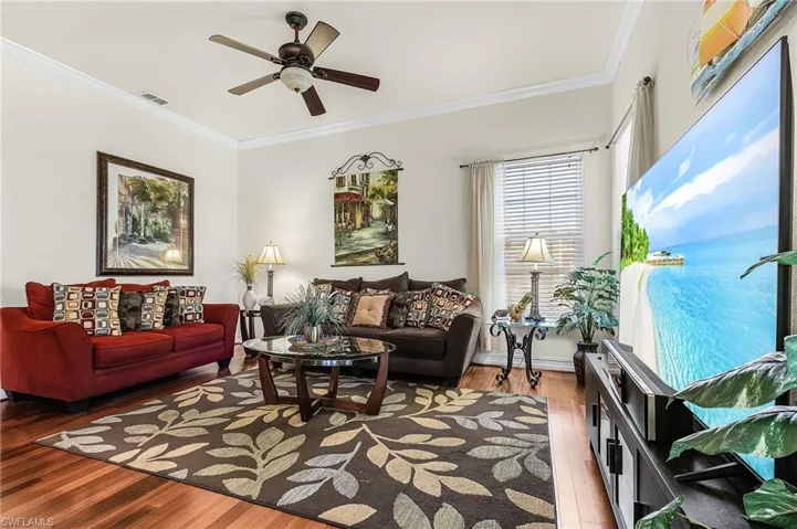 Living area featuring hardwood flooring, a ceiling fan, and crown molding