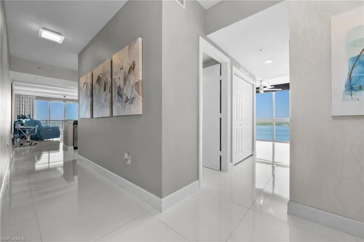 Hallway featuring floor to ceiling windows, light tile patterned floors, and a water view