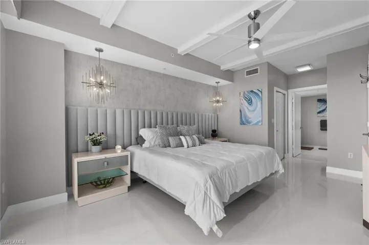 Bedroom with ceiling fan with notable chandelier and beam ceiling