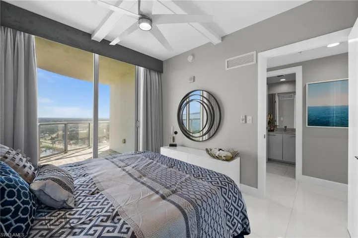 Tiled bedroom with ensuite bath, beamed ceiling, and ceiling fan