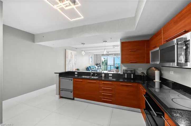 Kitchen with light tile patterned flooring, hanging light fixtures, sink, and black appliances