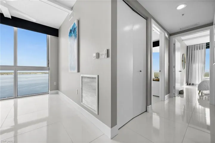 Hallway with a wall of windows, light tile patterned floors, and a water view