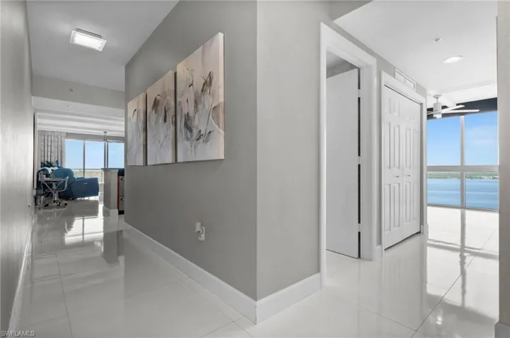 Hall with light tile patterned flooring, a wall of windows, and a water view