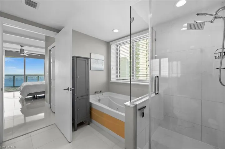 Bathroom featuring ceiling fan, shower with separate bathtub, and a water view