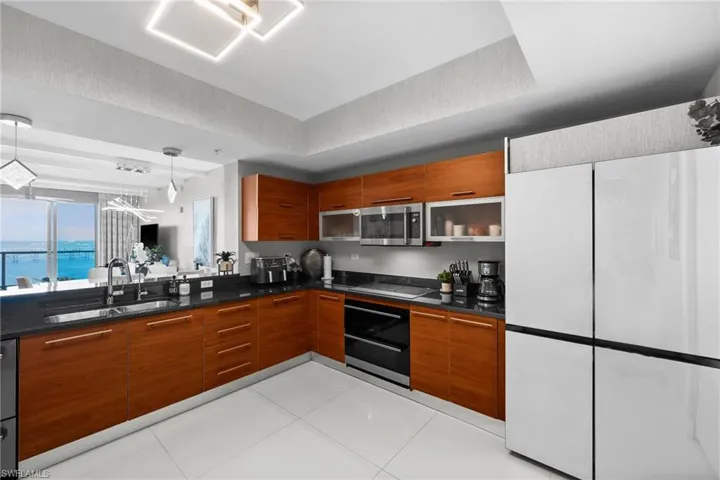 Kitchen featuring light tile patterned floors, stovetop, hanging light fixtures, and sink