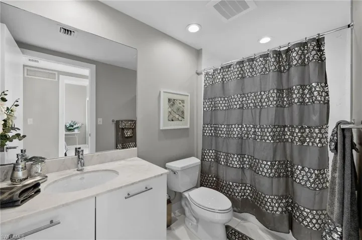 Bathroom featuring vanity, toilet, and curtained shower