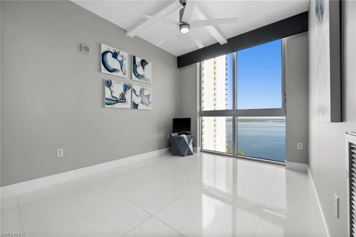 Empty room with tile patterned floors, beam ceiling, and ceiling fan