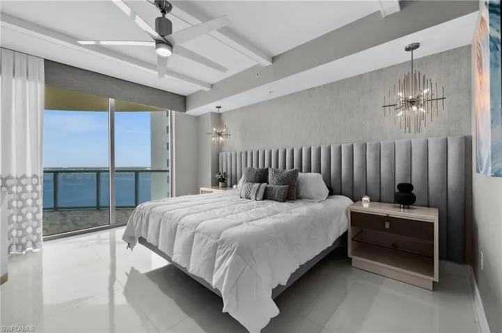 Bedroom with access to outside, beamed ceiling, light tile patterned flooring, ceiling fan with notable chandelier, and a water view