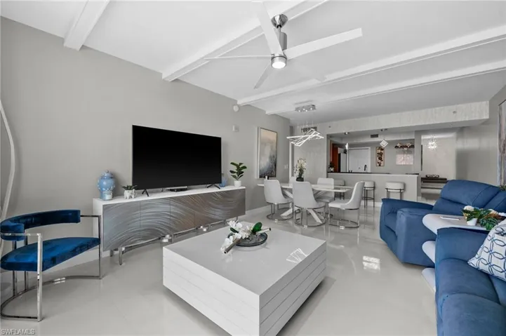 Living room with light tile patterned flooring, beamed ceiling, and ceiling fan