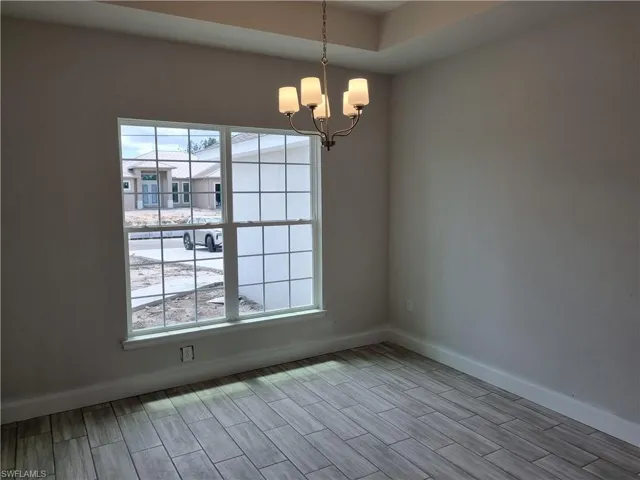 Empty room with hardwood / wood-style flooring and a chandelier