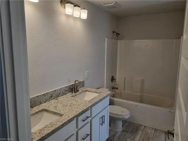 Full bathroom with shower / tub combination, wood-type flooring, toilet, and vanity