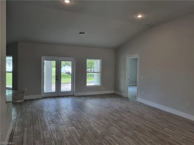 Spare room with french doors, dark hardwood / wood-style flooring, and lofted ceiling