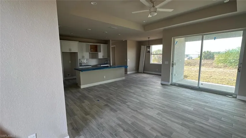 Kitchen featuring white cabinets, decorative light fixtures, sink, ceiling fan, and a tray ceiling